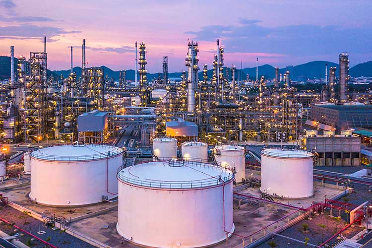 Aerial top view oil and gas chemical tank with oil refinery plant background at twilight.